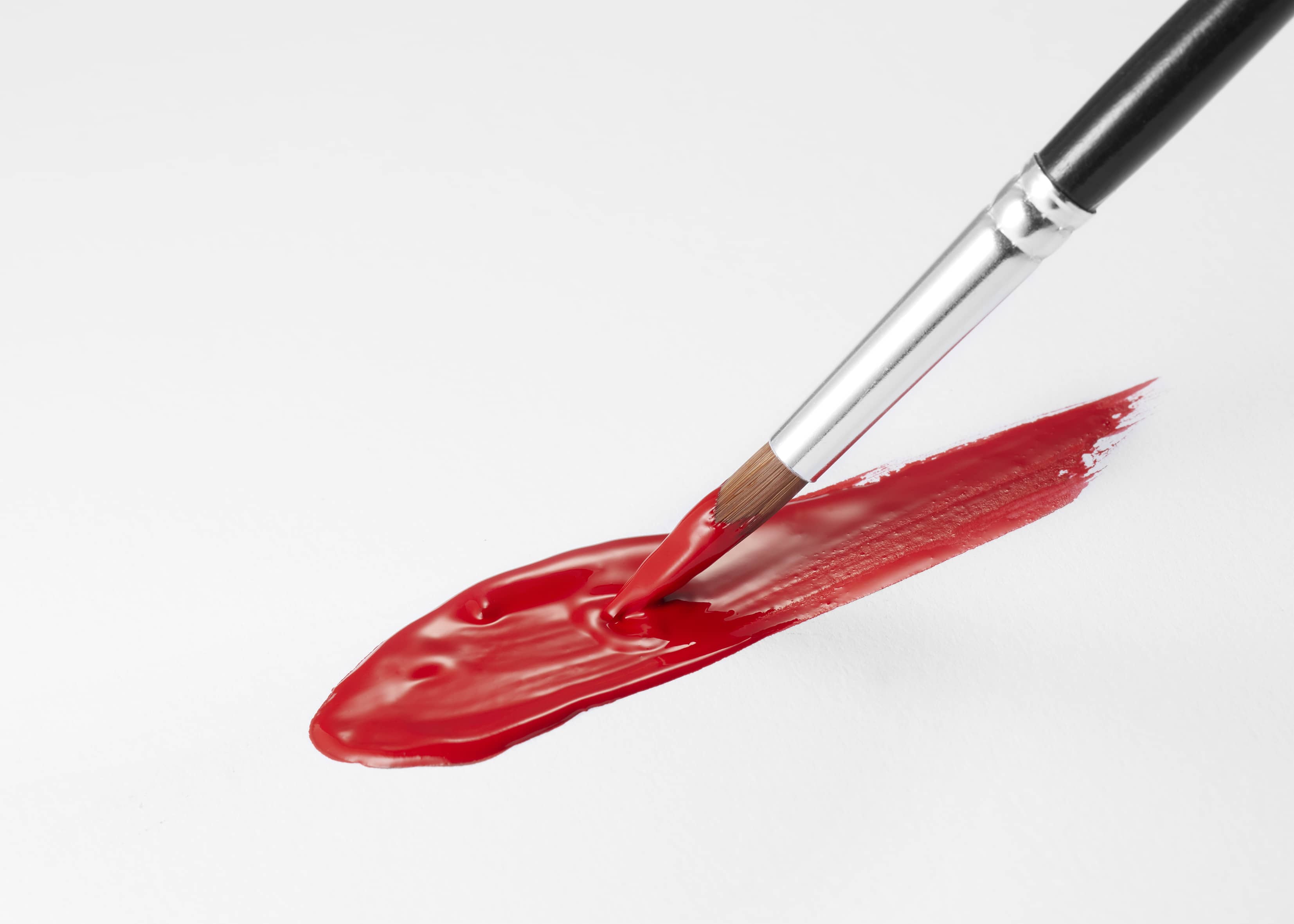 Lifestyle textured picture of red gouache with a brush